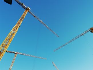 Kräne stehen für die Umsetzung von Planungen. Im Vorfeld sollten Zielkonflikte im Bereich Luftschadstoffimmissionen und Lokalklima geklärt sein.